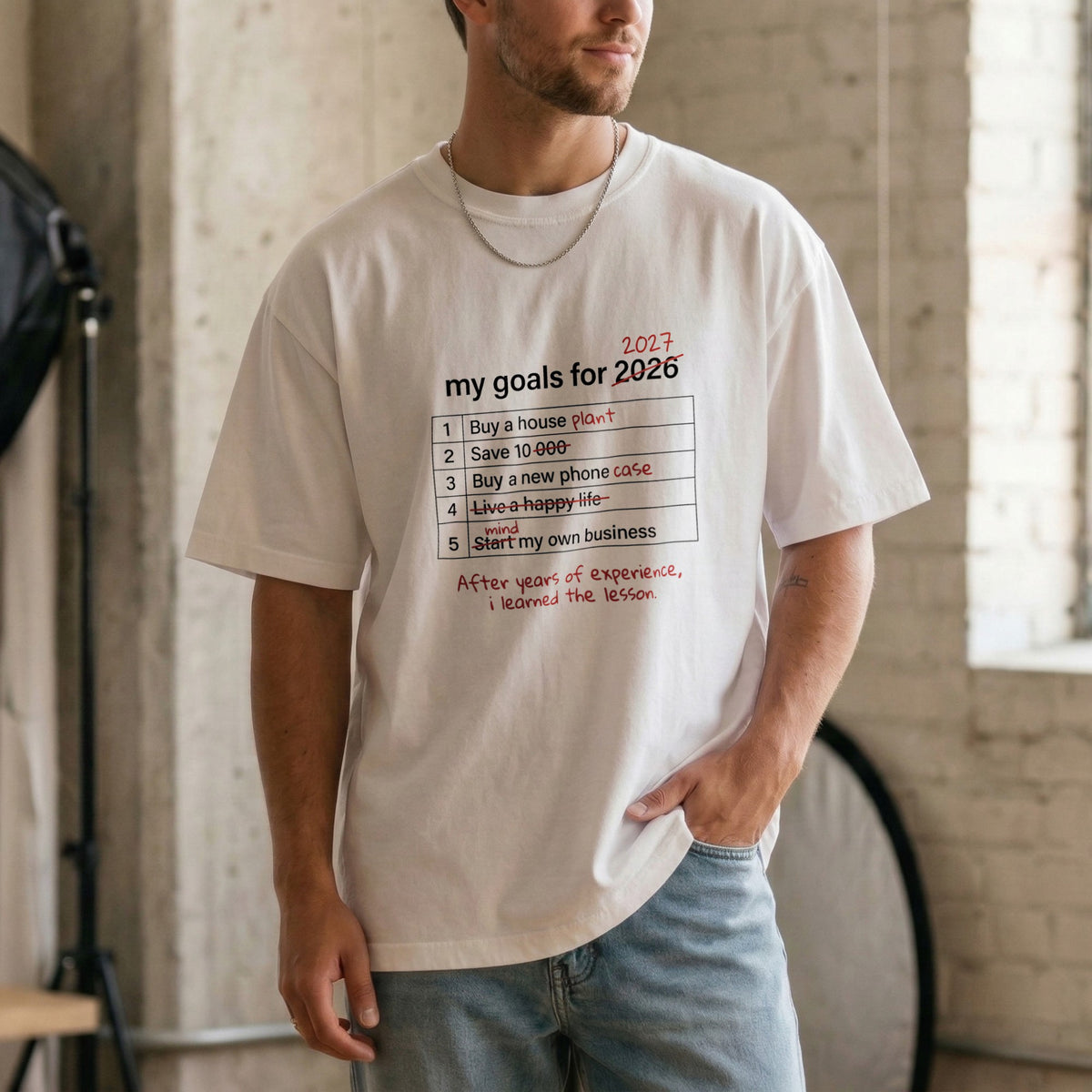 My Goals for 2027 white t-shirt on a model – funny New Year resolutions list with crossed-out goals like buy a house plant, Comfort Colors 1717