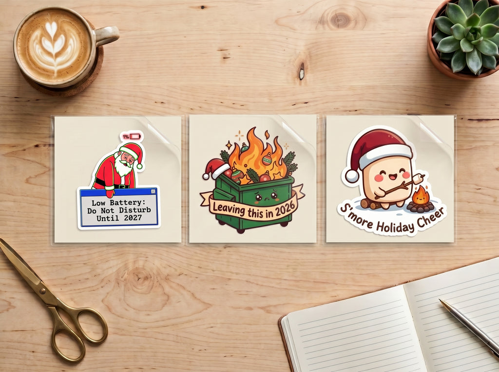 Holiday Survival sticker bundle – Low Battery Santa, Leaving This in 2026 and S'more Holiday Cheer Christmas stickers side by side on a wooden desk